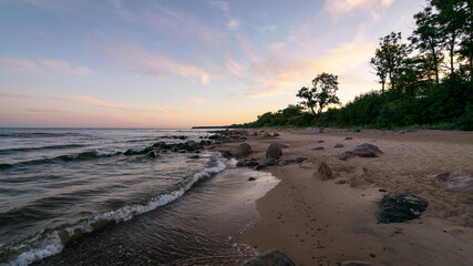 rocky sea shore before sunrise, dark stone silhouettes and colorful sky