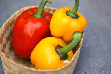 Blurry photo of colorful paprika in a baskets. red and yellow paprika in wicker basket on gray background