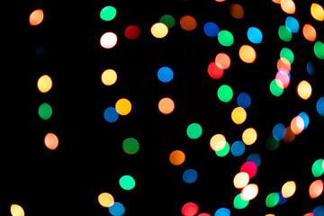 A brilliant glowing background side on black. The glitter light bokeh for the New Year and other holidays.