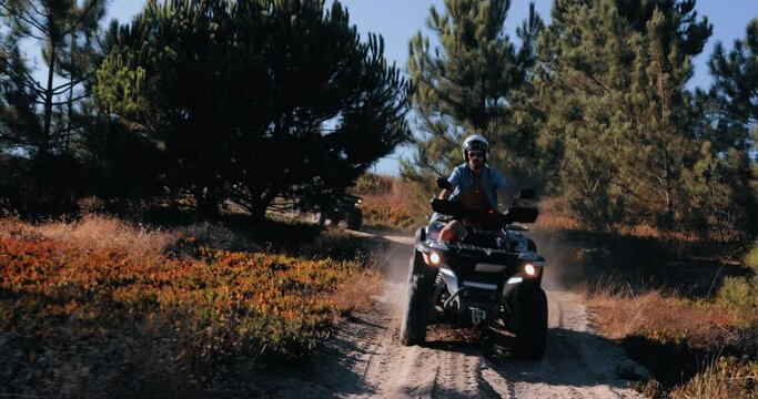 Friends with helmets riding quad bikes together in the forest