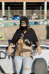 Mujer joven con mascarilla con skate monopatín en skatepark haciendo fotos selfies