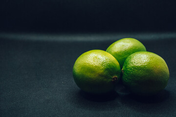 Three green limes on black background. Shallow depth of focus, blur, fruit, 3, trio.