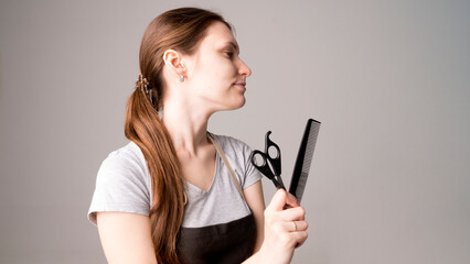 Young beautiful female hairdresser holding  hair clipper