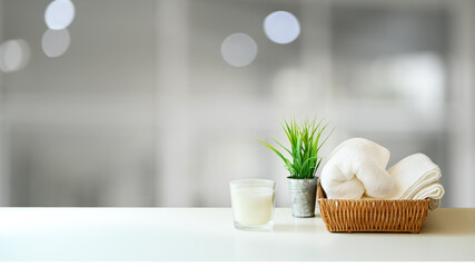Spa accessories with white towel and candle in wooden tray and copy space on white.