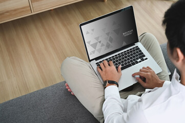 Young man freelancer working online with laptop and sitting on the couch at home.