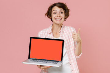 Smiling young brunette woman 20s wearing casual checkered shirt standing hold laptop pc computer...