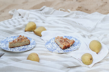 Having a picnic on a sand with a pears cake 