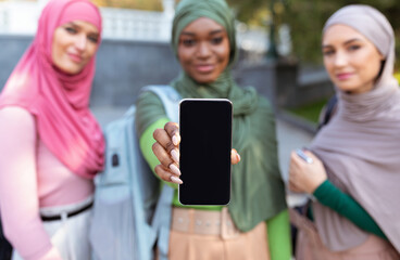 Three Muslim Women Showing Smartphone Screen Outdoors, Focus On Phone
