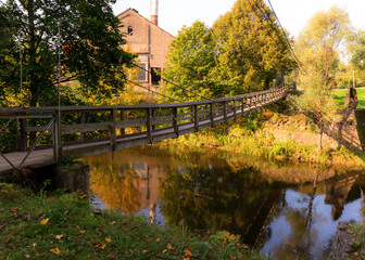 Fototapeta na wymiar wooden bridge over the river, trees and shrubs in the background