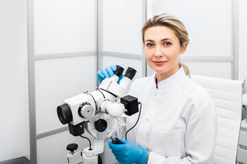 Portrait positive gynecologist woman sitting near a colposcope in her gynecological office....
