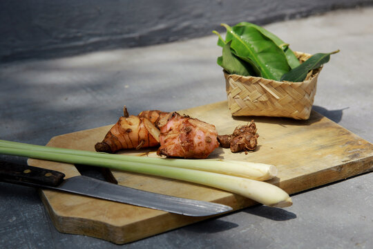 Indonesian traditional spices, various cooking spices. Lemongrass leaves, kencur, ginger, galangal, bay leaves and orange leaves on a cutting board with knife