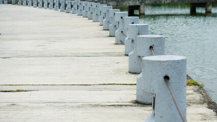 Concrete pedestrian walkway protection near a lake in a park. White small concrete posts on a walkway.