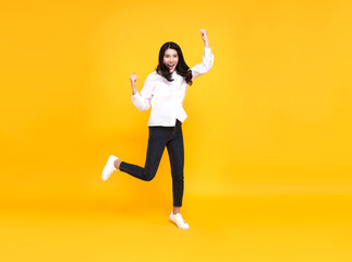 Fototapeta na wymiar Happy Asian woman smiling and jumping while celebrating success isolated over yellow background.