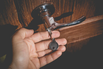 A man holds in his hand a small light broken key against the background of a door lock.