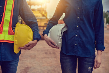 Two engineer holding hard hat on site construction