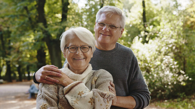 Happy old couple hugging in park. Senior man flirting with elderly woman. Autumn day. High quality photo