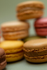 Colored tasty macaroons over a green background.