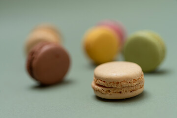 Colored tasty macaroons over a green background.