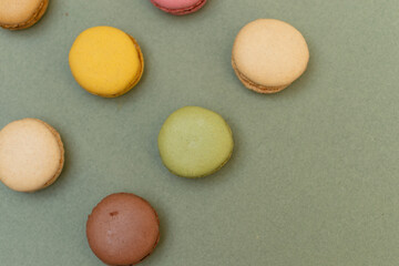 Obraz na płótnie Canvas Colored tasty macaroons over a green background.