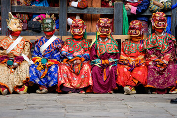 Fototapeta na wymiar Bhutan, in the village of Bumthang, superior monks in colourful costumes and masks sitting during the yearly festival of Jakar. 