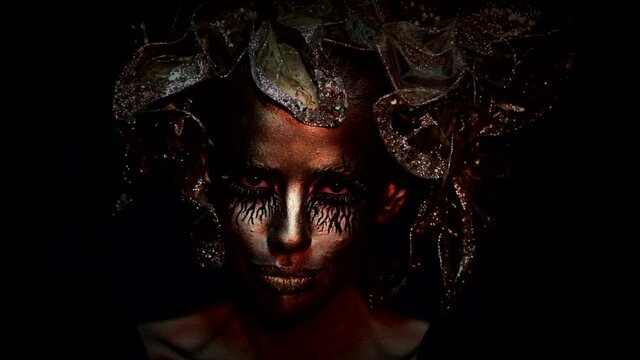 Slow motion. Creative art project. Golden young woman. Halloween female model, face in gold. Halloween fashion makeup. Women golden face.