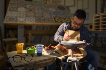 Artigiano decora a mano una piastrella di ceramica nella sua bottega