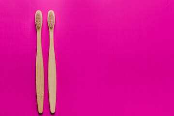 Bamboo toothbrushes on pink background, top view