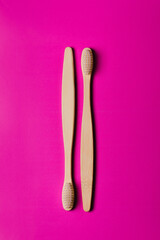 Bamboo toothbrushes on pink background, top view