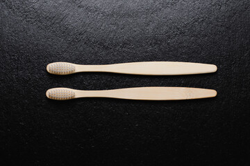 Bamboo toothbrushes on black background, top view