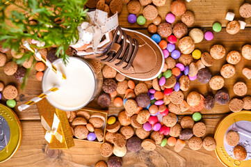 Fototapeta na wymiar Dutch holiday Sinterklaas. Wooden background with childrens shoe with carrots for Santa's horse, pepernoten and sweets . View from above. High quality photo