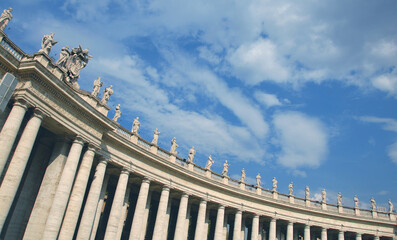 The famous colonnade of St. Peter's Square with statues in the Vatican state that is formed by large columns of travertine in a circular shape.