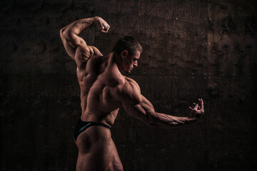 Sporty and healthy muscular man from back on dark grunge background - 386396542