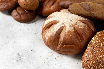 Rye bread. Rye bread of different shapes on a light gray table. Baguettes, loaves, round bread and rolls on the table. Copyspace