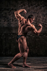 Sporty and healthy muscular man on dark grunge background - 386397595