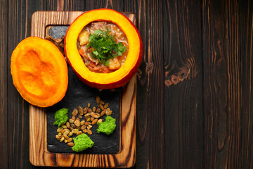 Roast with meat and potatoes in a pumpkin, on a wooden background with fried pumpkin seeds