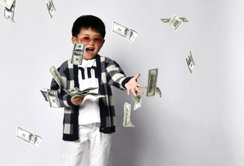 Happy shouting self-confident asian rich kid boy millionaire standing with bunch of moneys throwing...
