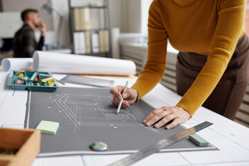 Cropped shot of unrecognizable female architect drawing blueprints and plans while working at desk...