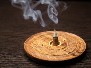 Burning cone incense on wooden holder
