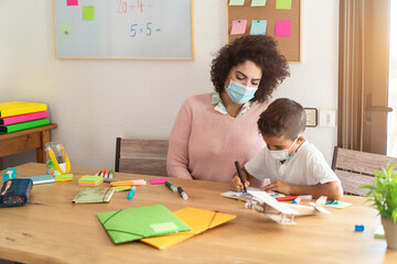 Teacher and child wearing protective face masks in classroom during coronavirus outbreak - Back to...