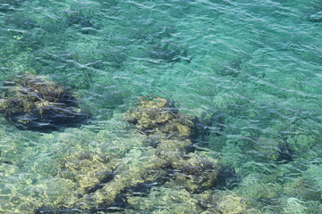 Underwater rocks, transparent sea surface with a rocky bottom.  Aerial view to azure water, natural blue background