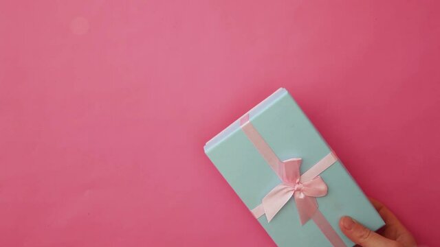 Simply design female woman hand holding blue gift box isolated on pink pastel colorful trendy background. Christmas New Year birthday valentine celebration present romantic concept. Copy space