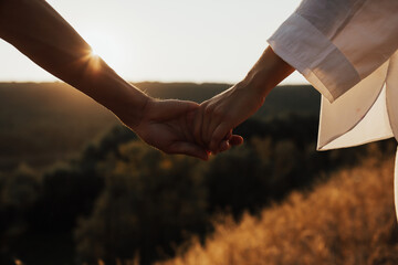Close up of  couple holding hands on the hill. Close up of hands.