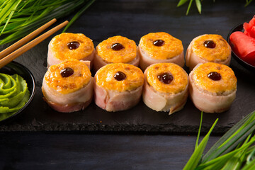 Set of baked sushi rolls with wasabi and ginger on black - obrazy, fototapety, plakaty