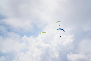 Paragliding in the cloudy blue sky.