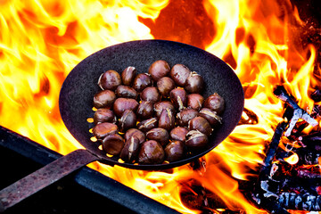 roasting chestnuts in a skillet with holes on the fire