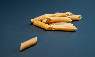 Yellow raw macaroni, a close-up of traditional Italian pasta, uncooked noodles on black background.