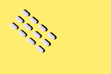 background image of white pills on a yellow background.