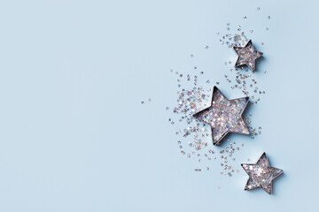 Christmas and happy new year flat lay with shape of stars and confetti glitter on blue background