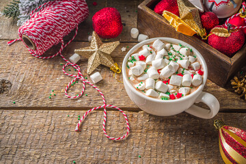 Hot chocolate with marshmallows, warm chocolate drink for Christmas morning breakfast, on wooden background with Christmas decorations, cozy winter pic copy space