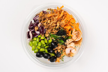 Salad with carrots, red cabbage, shrimps, seaweed, edamame beans, olives, caramelized onions, dill, sesame seeds in a bowl on a white background.
